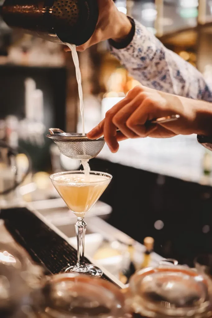 Préparation d'un cocktail avec du gin acolyte et d'autres ingrédients par le barman.